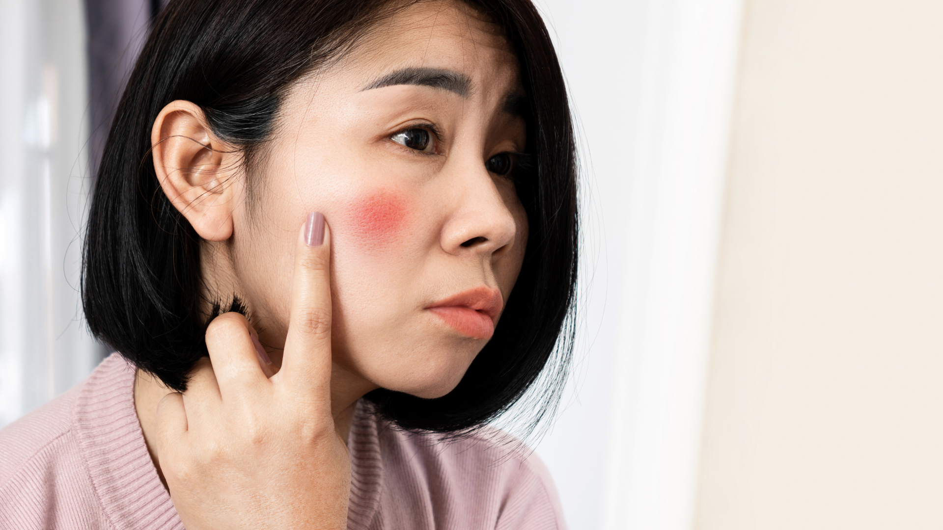 Femme avec un carré brun présentant une rougeur cutanée sur la joue et la montrant du droit